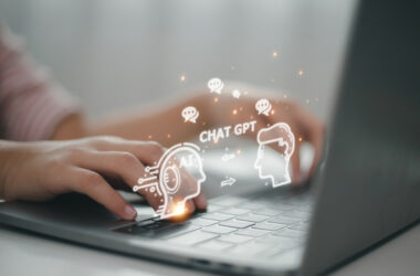 Hands are typing on a laptop, and glowing speech bubble icons emerge that say, “AI, Chat GPT.”