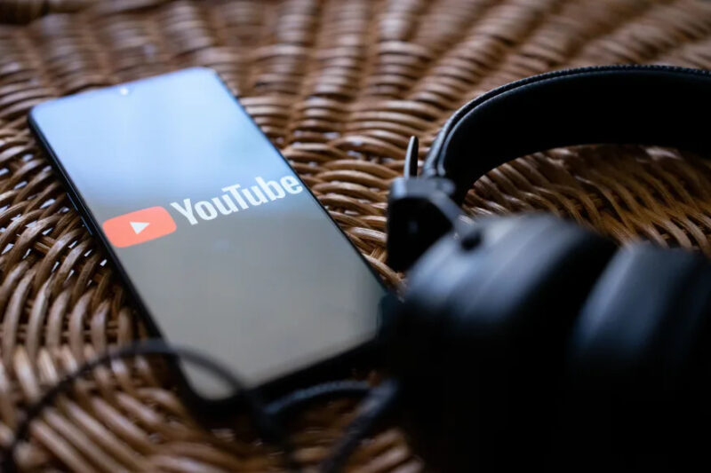 Headphones connected to a mobile phone with the logo of You tube on its screen. (Photo by Nikos Pekiaridis/NurPhoto via Getty Images)