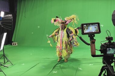 Dancer in Indigenous ceremonial dress front of a green screen